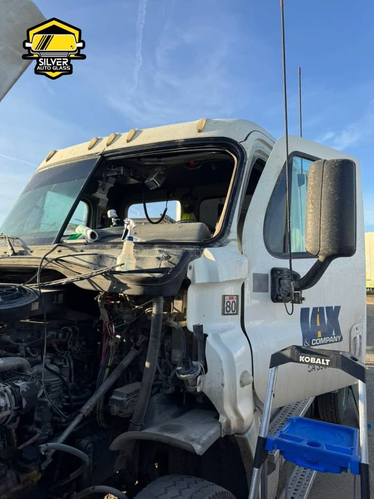 Damaged white Kobalt semi truck cab with broken windshield at auto glass repair facility