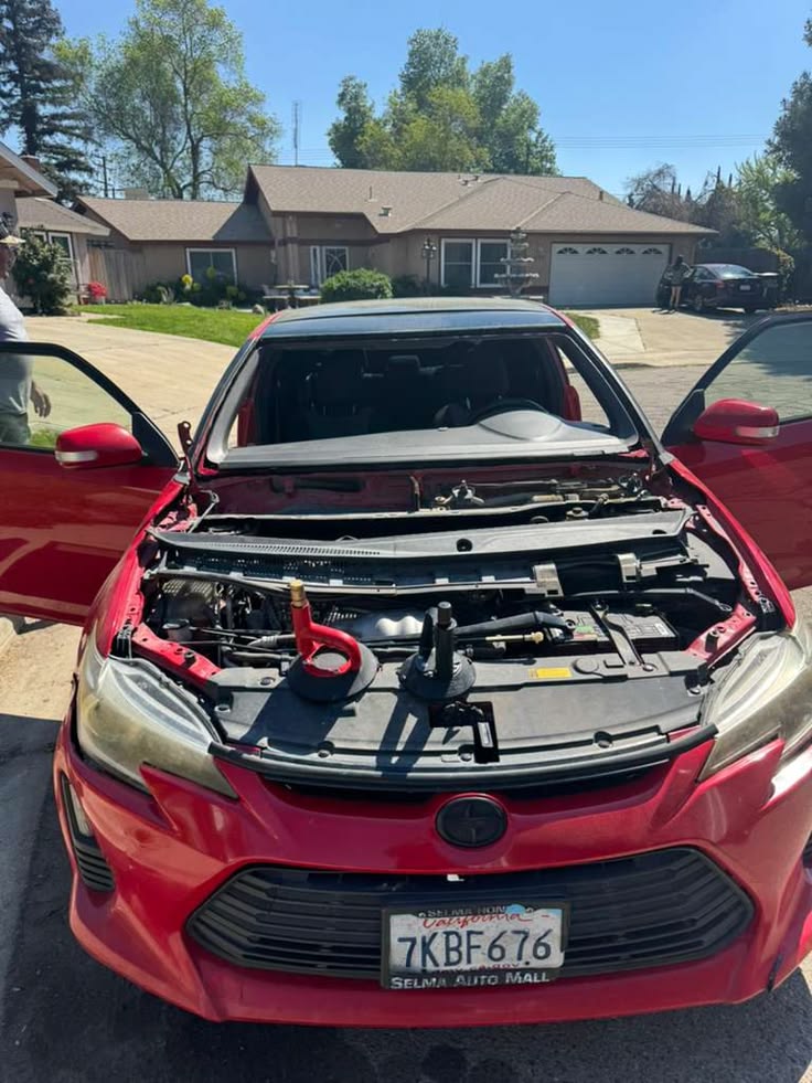 Red Toyota with open hood displaying engine in driveway
