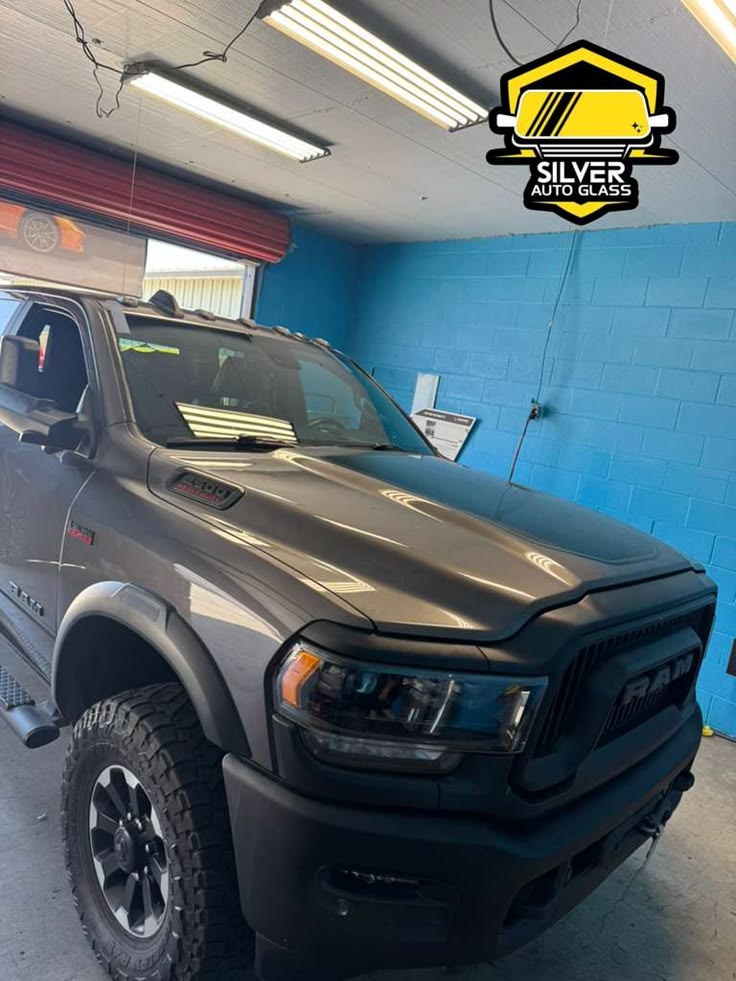 Black pickup truck with windshield tint in auto glass shop with Silver Auto Glass logo