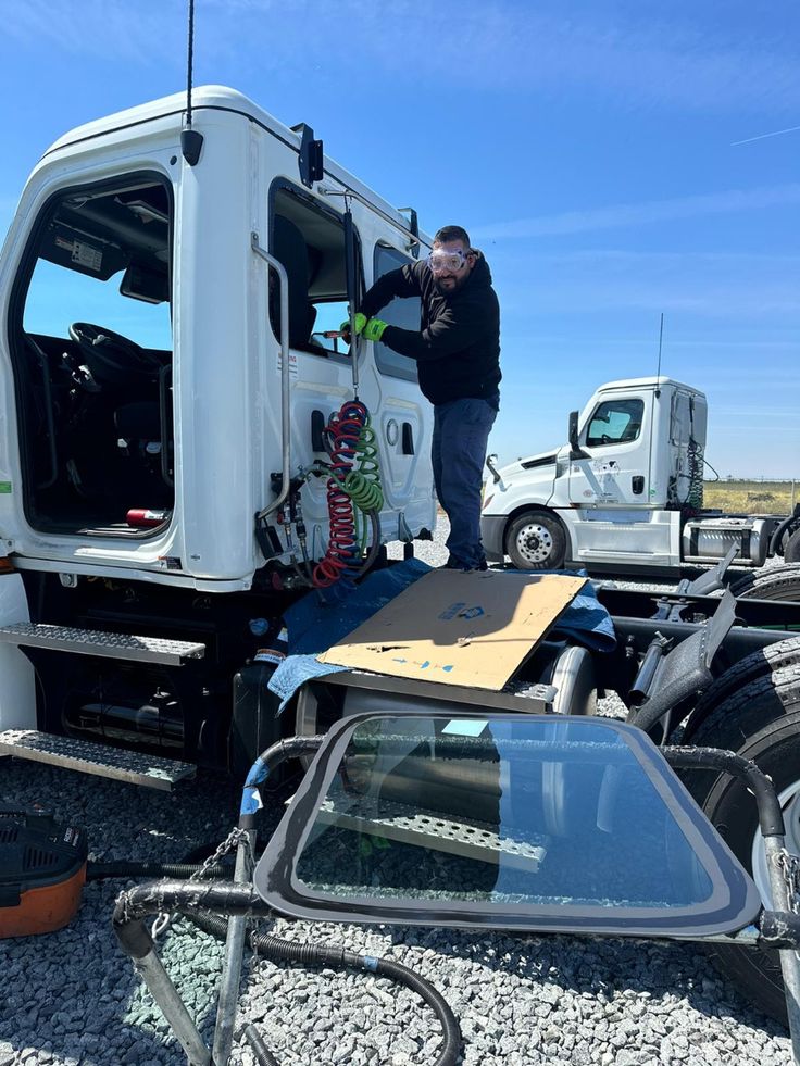 Man inspecting white semi truck cab on transport trailer in sunny lot