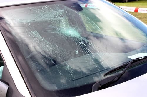 Cracked car windshield with impact point and radiating fractures